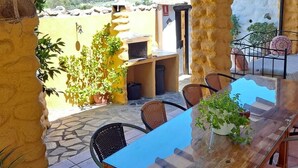 An outdoor patio with a wooden table and chairs, surrounded by stone walls and potted plants. - Houses Amaro.   Spacious, comfortable, cozy and wonderful views  (0rgiva)