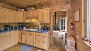 L’intérieur d’une cabane en bois comprend une cuisine équipée d’armoires en bois, d’un évier et d’une cuisinière.