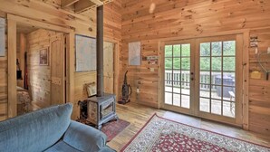 L'intérieur d'un chalet en bois comprend un canapé, un petit radiateur et une grande porte-fenêtre coulissante qui donne sur une terrasse extérieure.