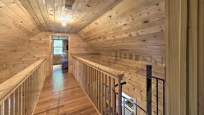 Un intérieur en bois avec un escalier central, des murs en bois et une porte visible donnant sur une autre pièce.