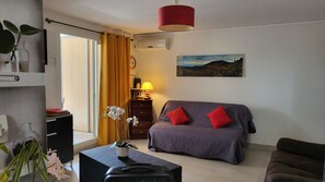A room with a bed, a desk, a chair, a lamp, and a painting on the wall.