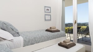 A bedroom with a bed, a bedside table, and a view of the outdoors through a sliding door. - Twin villas with large pool and sea views near Barcelona. Free wifi, a / c (Sant Pol de Mar Barcelona)
