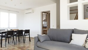 A modern living room with a grey sofa, black chairs, and a dining table. - Twin villas with large pool and sea views near Barcelona. Free wifi, a / c (Sant Pol de Mar Barcelona)