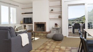 A modern living room with a fireplace, a sofa, a TV, and a balcony with a view. - Twin villas with large pool and sea views near Barcelona. Free wifi, a / c (Sant Pol de Mar Barcelona)