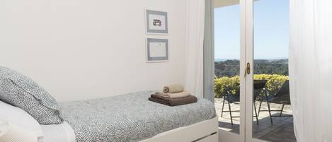 A bedroom with a bed, a window, and a view of the outdoors.