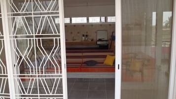 Ein Zimmer mit einer Schiebeglastür, einer Küchenzeile inklusive Herd und Spüle sowie einem Sofa mit Kissen.