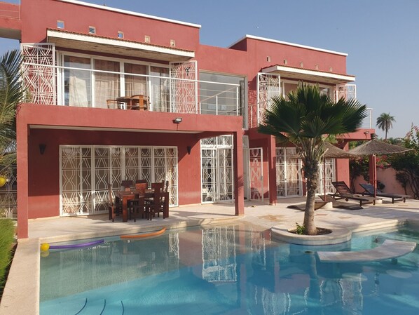 A modern hotel with a swimming pool, outdoor seating, and a two-story structure with balconies.