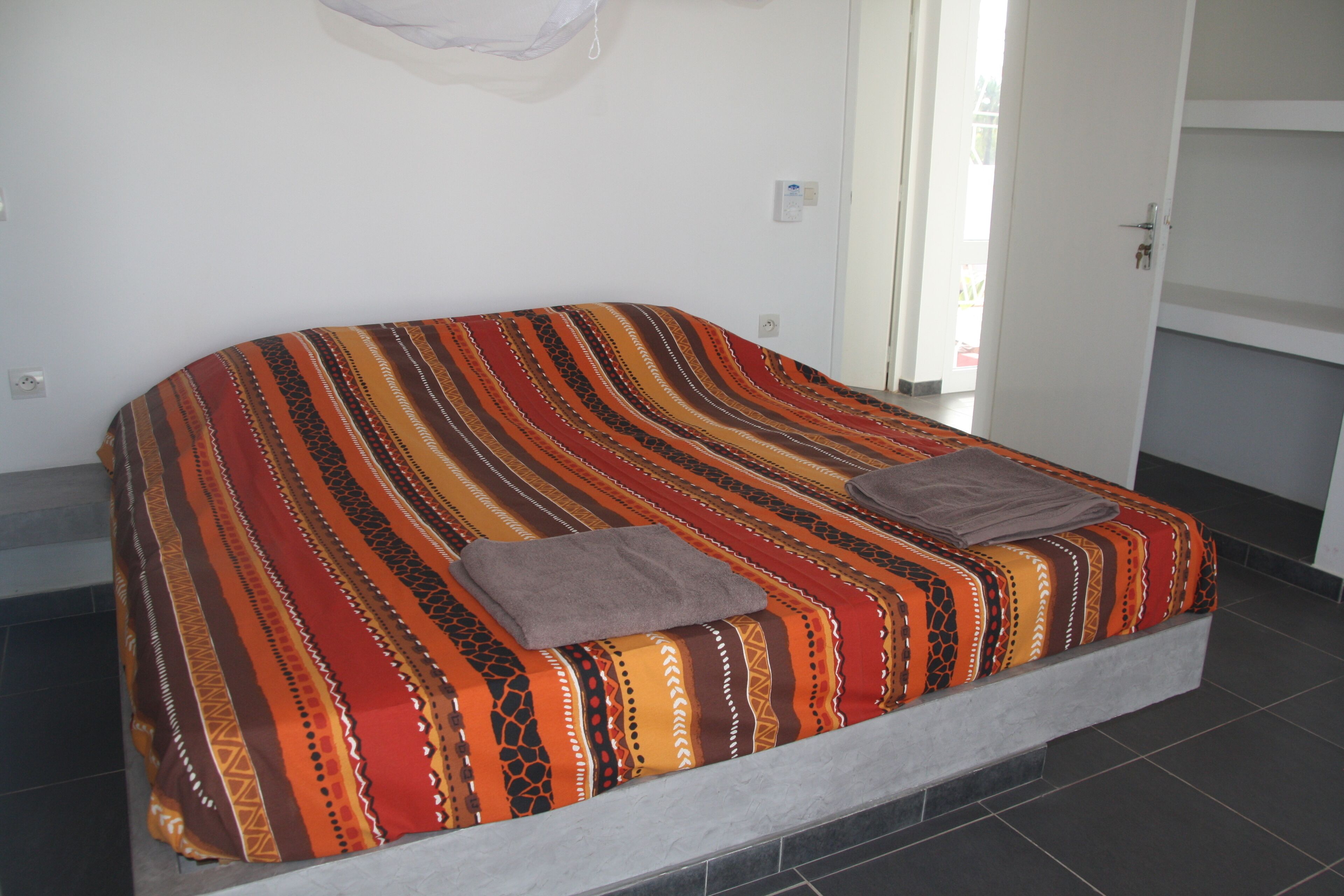 Una cama con una colcha a rayas de colores y dos almohadas.