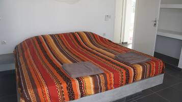 Una cama con una colcha a rayas de colores y dos almohadas.