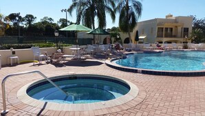 Un área de piscina con sillones de descanso y una bañera de hidromasaje.
