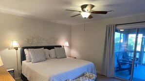Una camera da letto con un letto grande, due lampade da comodino, una ventola a soffitto e vista su una terrazza esterna attraverso una porta in vetro.