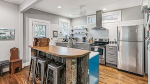 Uma cozinha moderna com ilha central, eletrodomésticos de aço inoxidável e espaço com banquetas.