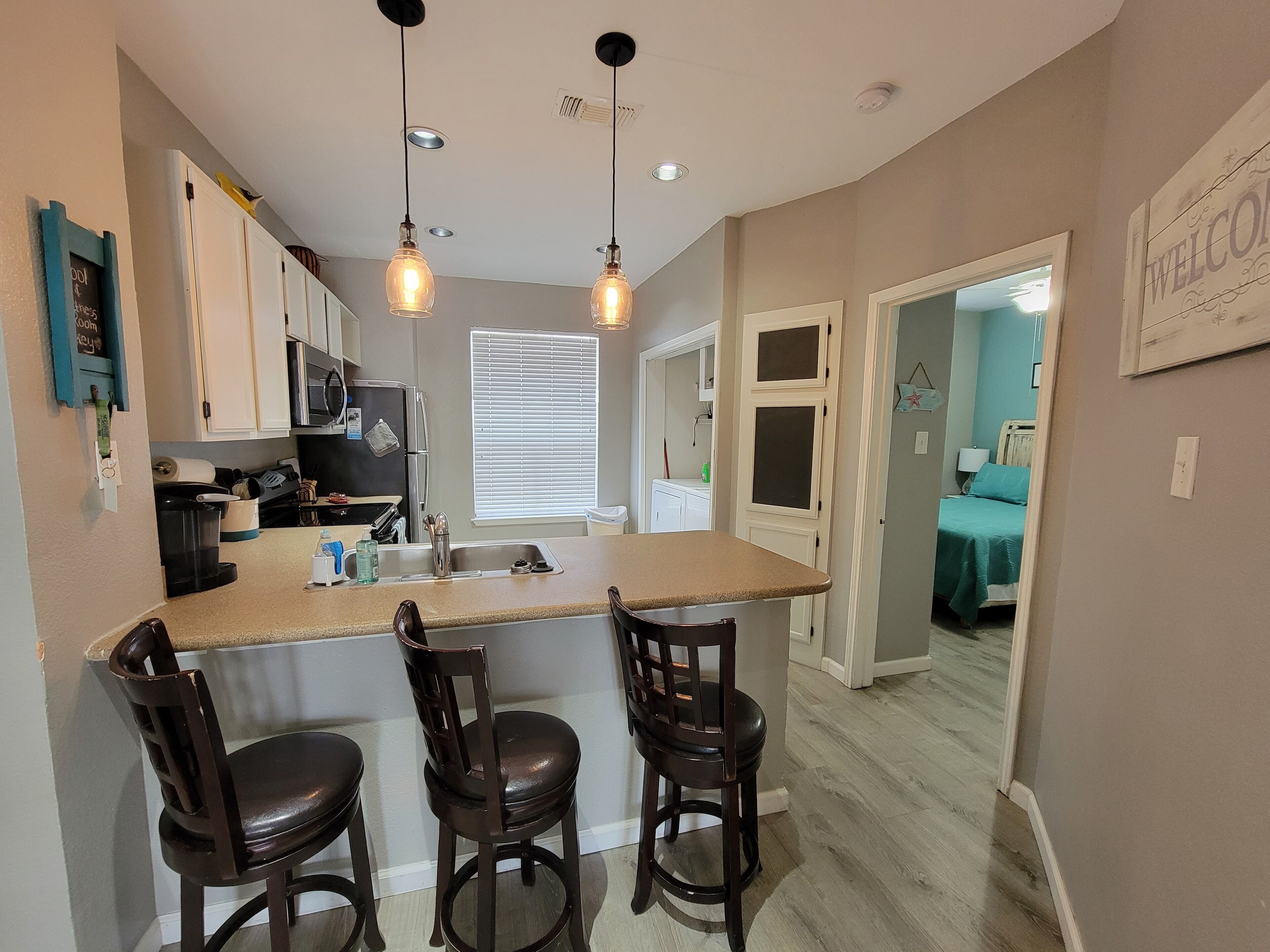 A kitchen with a central island, bar stools, and pendant lighting.