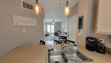 A kitchen with a double sink, a coffee machine, and a refrigerator.