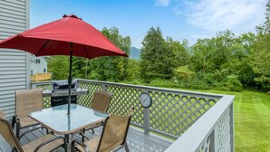 A deck with a glass table and chairs, a red umbrella, and a grill. - Enjoy each season's weather in historic Manchester.   Plenty to do year round!! (Manchester)