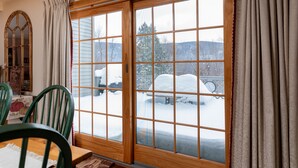 A room with a wooden-framed sliding glass door, a dining table with chairs, and a mirror on the wall. - Enjoy each season's weather in historic Manchester.   Plenty to do year round!! (Manchester)