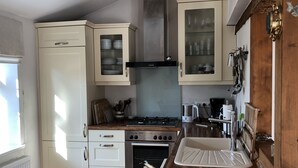 Kompakti keittiö, jossa on valkoiset kaapit, kaasuliesi, uuni ja pesuallas.