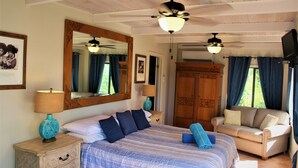 A bedroom with a large bed, a nightstand with a lamp, a dresser, a chair, a ceiling fan, and a TV. - 4 bedroom, 4 bathroom. Private Pool, Ocean views. Chocolate Hole, Cruz Bay. (St. John, VI)