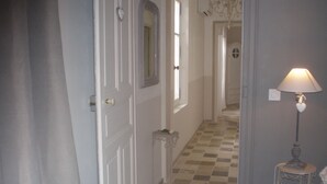 A hallway with a checkered floor, a lamp, and a door with a heart-shaped decoration.