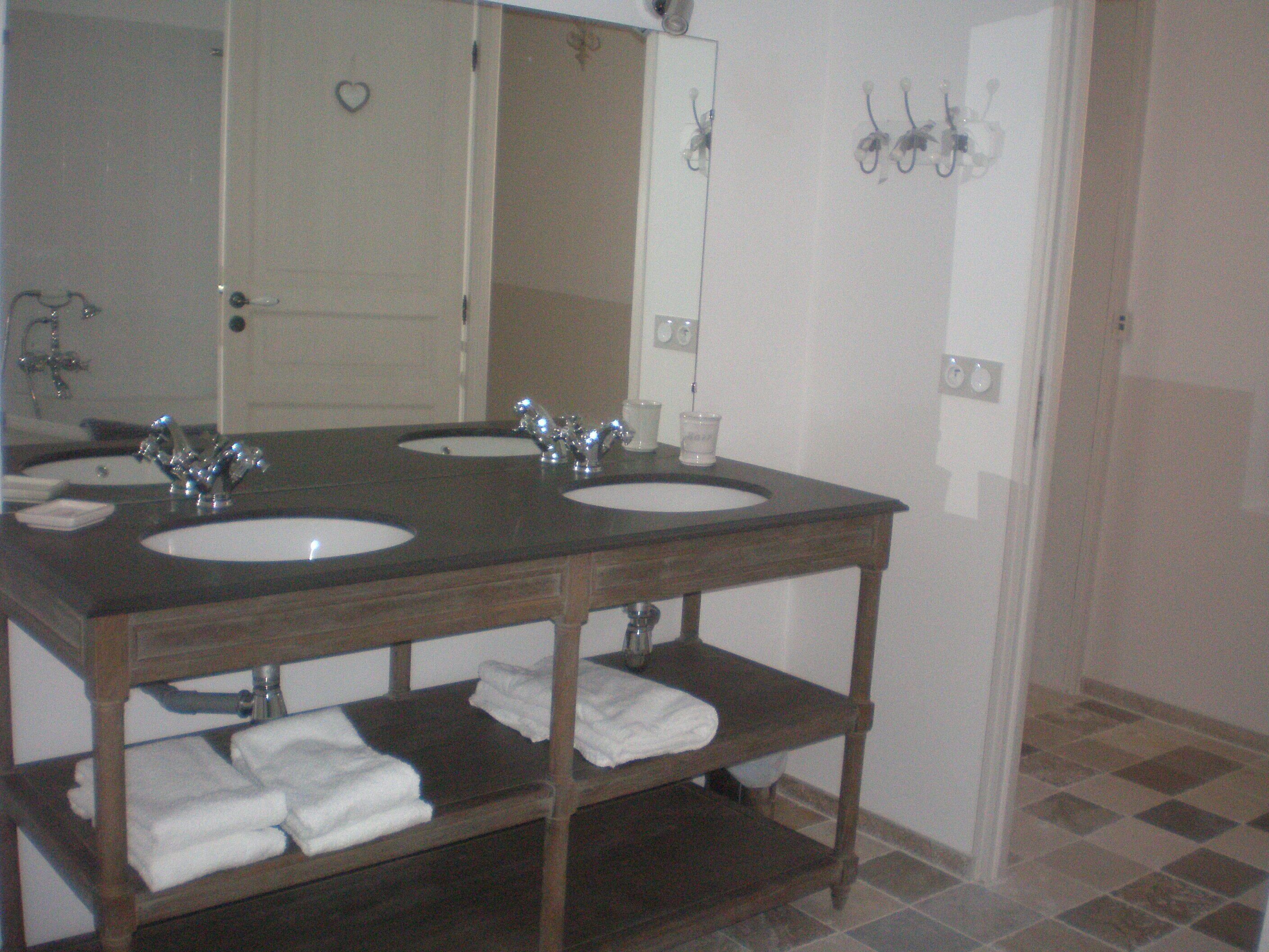 A bathroom with two sinks, a mirror, and a shelf with towels.