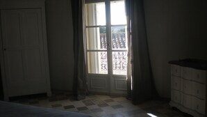 A room with a checkered floor, a bed, a wardrobe, and a window with curtains.