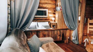 Een gezellig kamer in chaletstijl met houten inrichting, een bed, een nachtkastje met lamp en gordijnen.