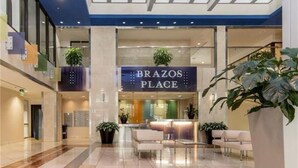 En lobby med reception, siddeområde og et skilt der siger "BRAZOS PLACE".