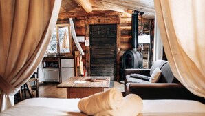 A cozy log cabin room with a bed, a wooden table, a sofa, and a fireplace. - Log cabin Les Convers (Collonges-sous-Salève)