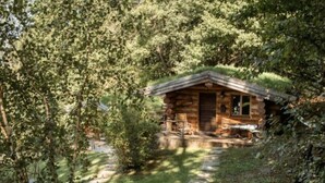 A rustic cabin with a thatched roof, surrounded by dense forest. - Log cabin Les Convers (Collonges-sous-Salève)