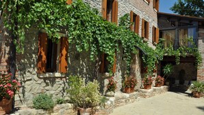 Un edificio de piedra con contraventanas de madera y plantas en macetas.