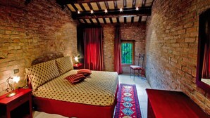 Un dormitorio con cama, mesita de noche, silla, ventana y alfombra roja.