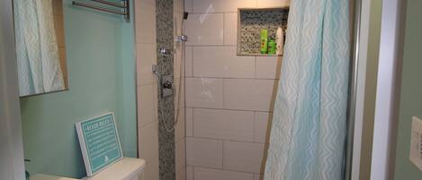 A bathroom with a toilet, sink, shower, and a towel rack.