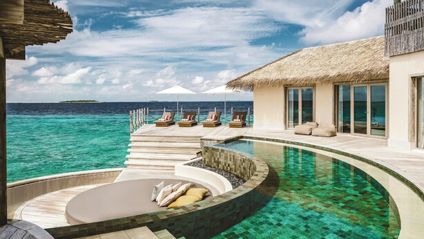 A resort pool with a circular seating area, lounge chairs, and a thatched-roof structure. - InterContinental Maldives Maamunagau Resort by IHG (Maamunagau Island)