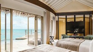 A spacious room with a large window overlooking a beach, a flat-screen TV, and a cozy seating area. - InterContinental Maldives Maamunagau Resort by IHG (Maamunagau Island)