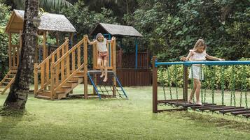 A playground with wooden structures, including a climbing area and a swing set.