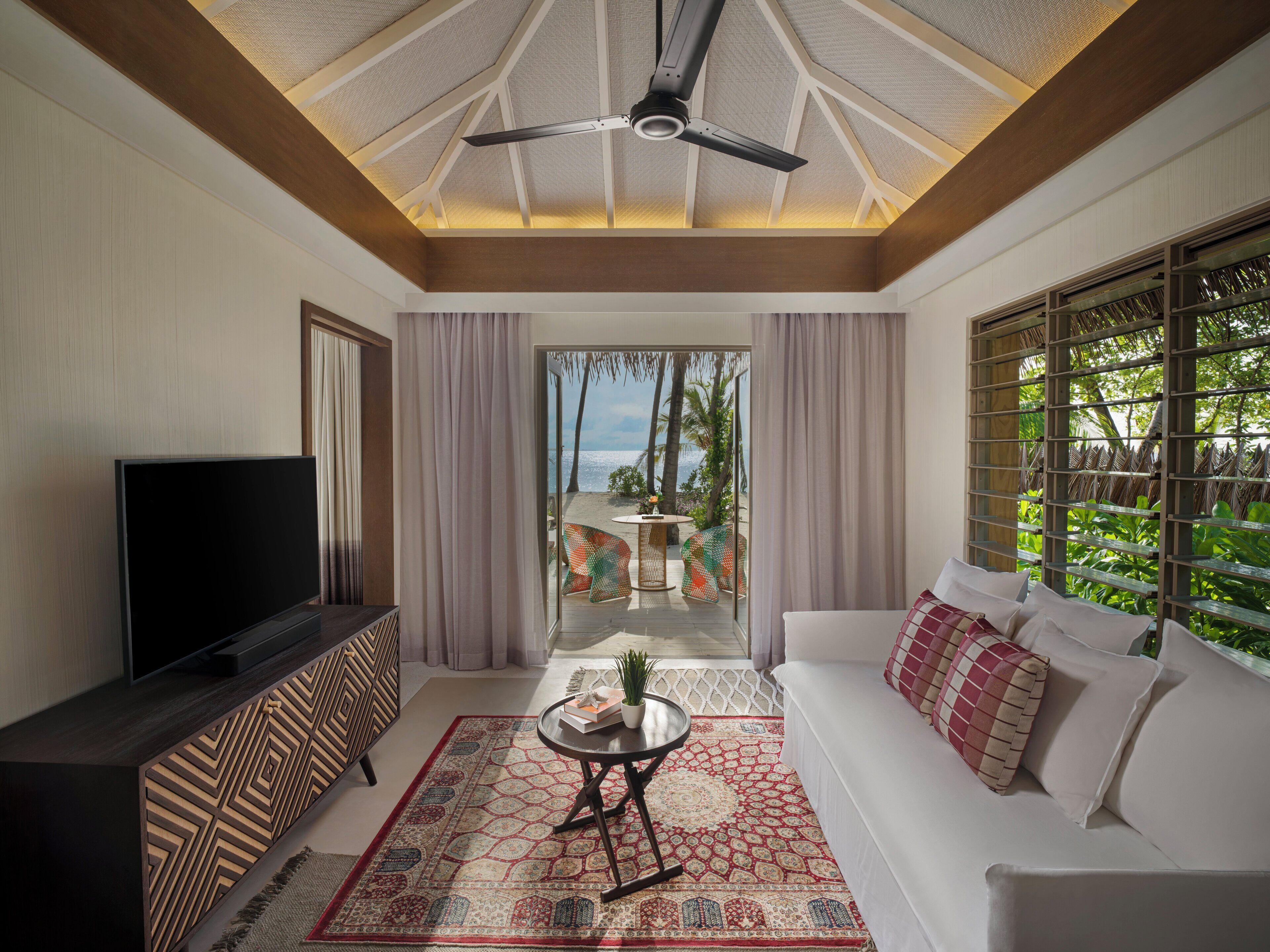 A modern living room with a TV, sofa, and a ceiling fan.