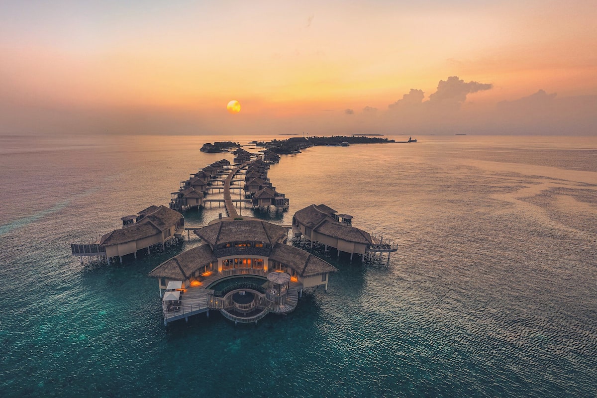 An overwater resort with multiple bungalow-style accommodations connected by walkways.