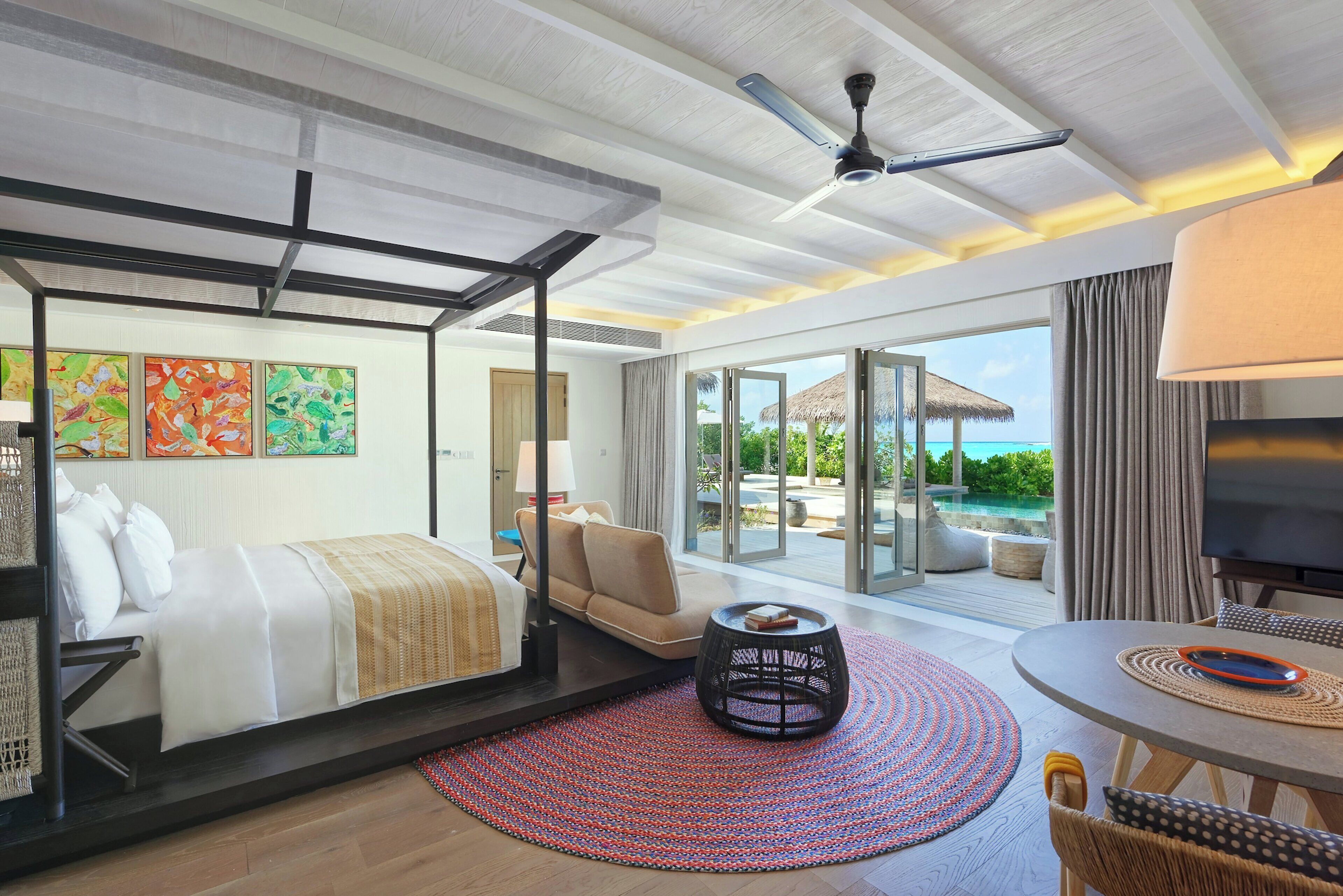 Una habitación de hotel con cama, zona de estar, televisión y vista al océano.