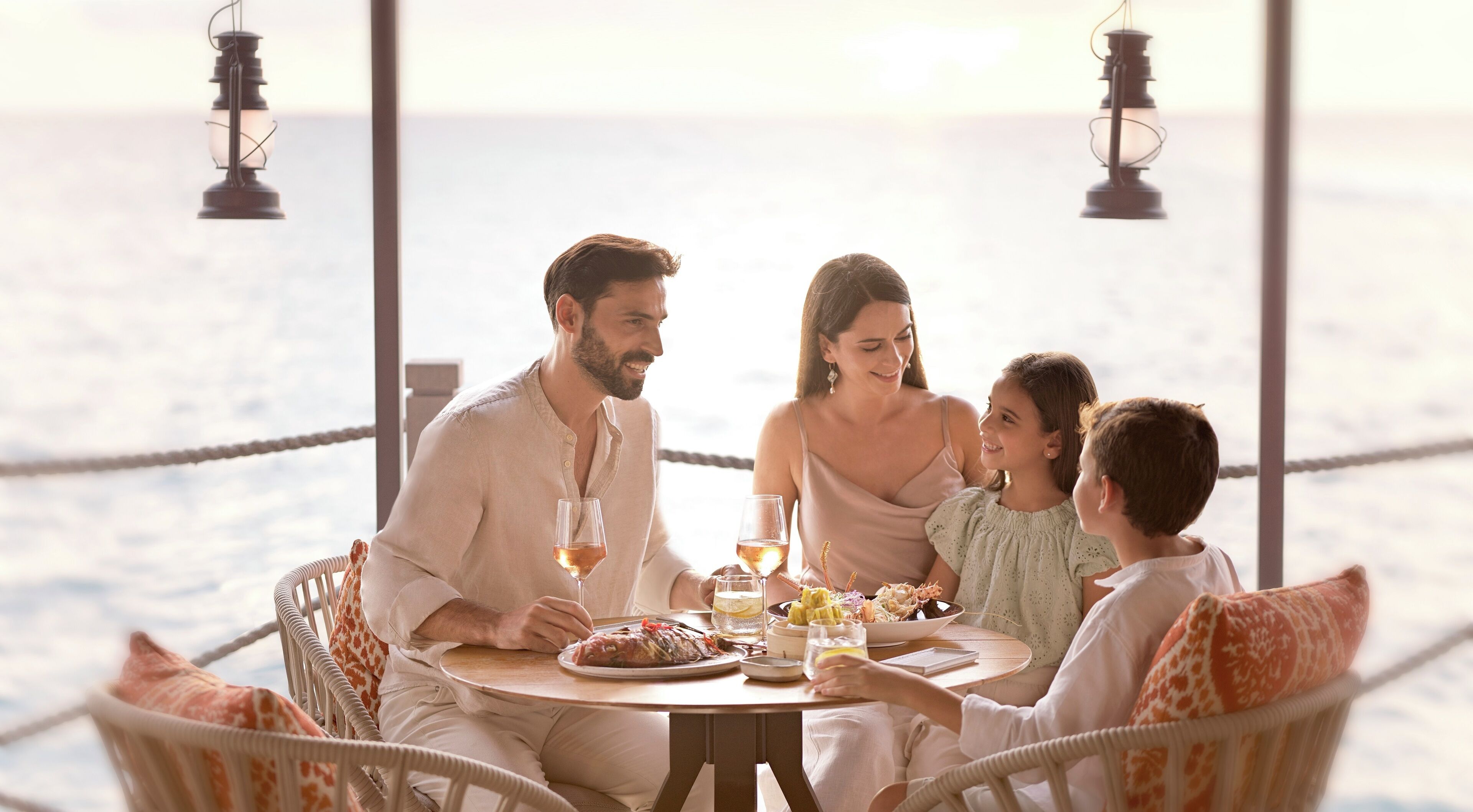 Una familia cenando en una mesa redonda con vista al mar.