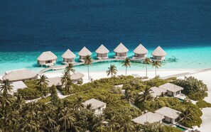 An aerial view of a resort with overwater bungalows, a beach, and lush greenery. - InterContinental Maldives Maamunagau Resort by IHG (Maamunagau Island)