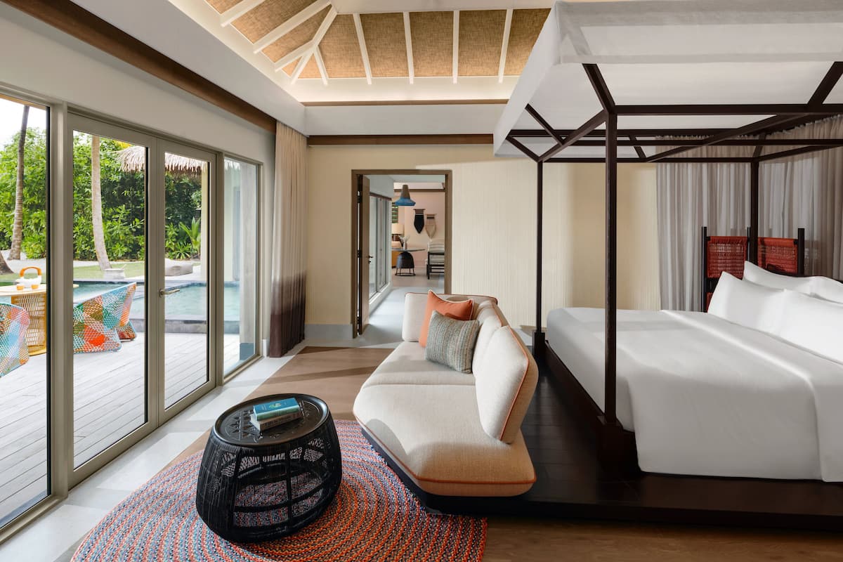 A modern hotel room with a large window, a sofa, a bed, and a small round table.