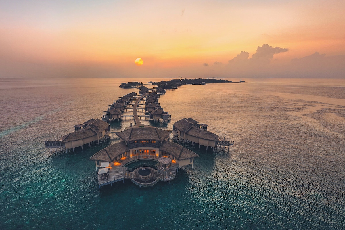 An overwater resort with multiple bungalow-style accommodations connected by walkways.