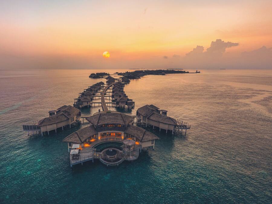 An overwater resort with multiple bungalow-style accommodations connected by walkways.