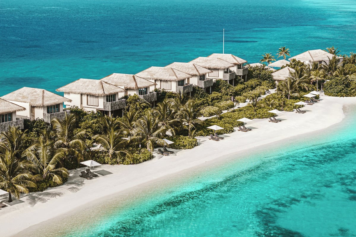 An aerial view of a beach resort with overwater bungalows, white sandy beaches, and clear turquoise waters.