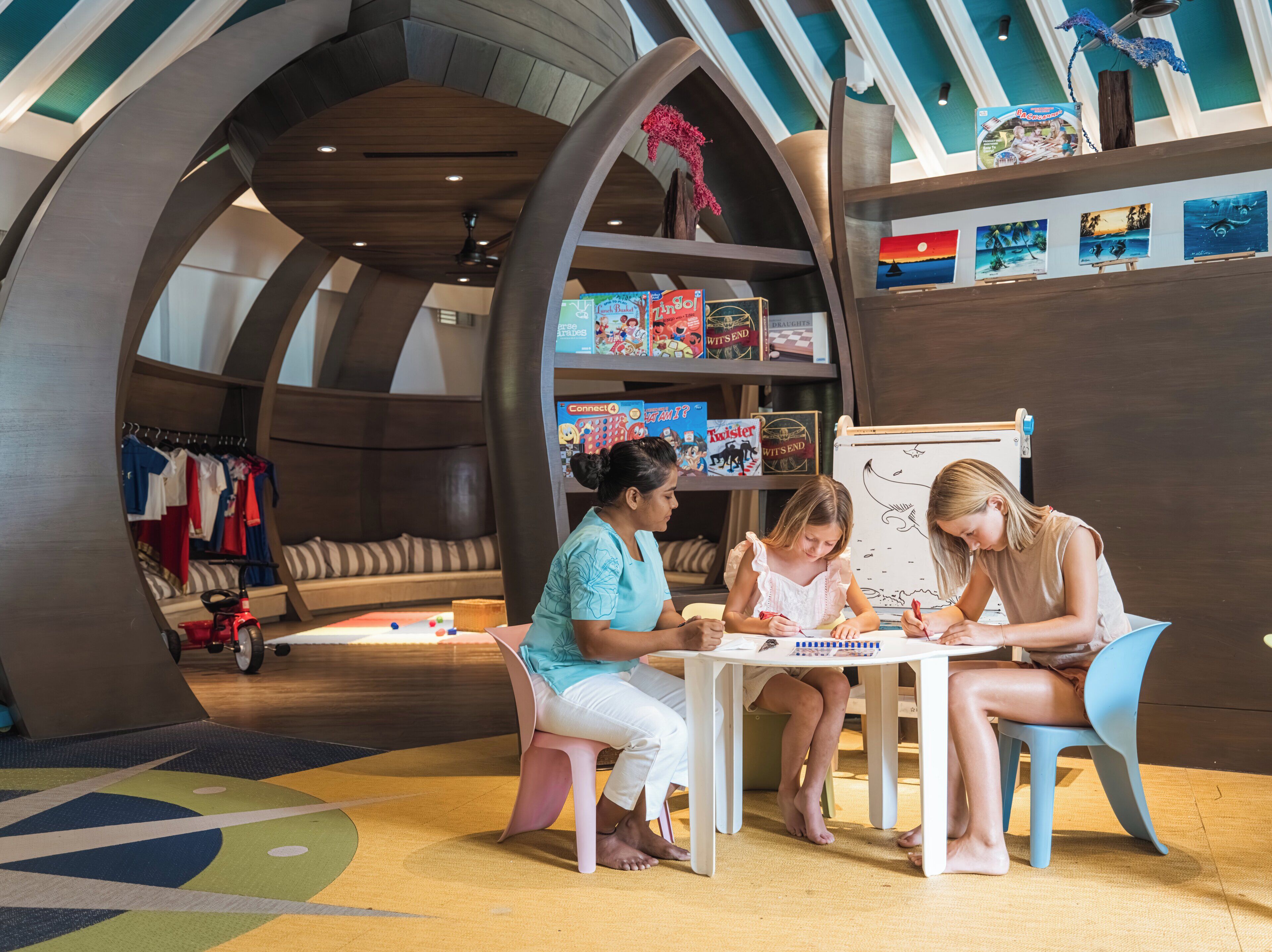 Un espace de jeux pour enfants avec une table, des chaises et un tableau blanc.