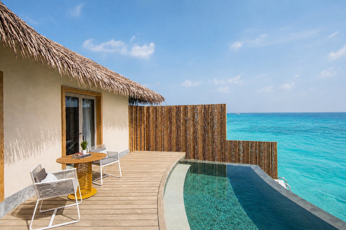 A wooden deck with a thatched roof, a pool, and a view of the ocean.