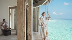 A wooden deck with a view of the ocean, a person in a robe, and another person in the background. - InterContinental Maldives Maamunagau Resort by IHG (Maamunagau Island)