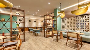 A modern cafe with wooden furniture, a green wall, and a decorative partition. - Holiday Inn Piura by IHG (Piura)