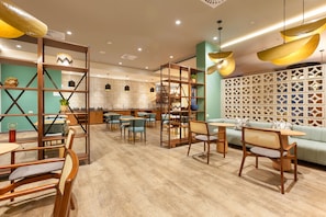 A modern cafe with wooden furniture, a green wall, and a decorative partition.