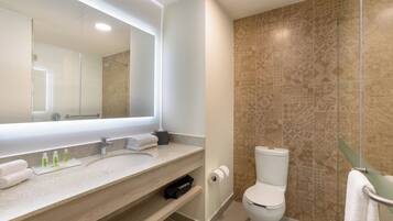 A modern bathroom with a large mirror, a sink, a toilet, and a shower area.
